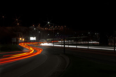 Light trails on road against sky at night