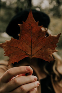 Close-up of woman holding dry maple leaf during autumn