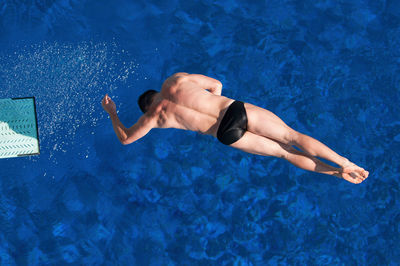 High angle view of shirtless man swimming in pool