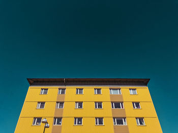 Low angle view of yellow building against clear sky