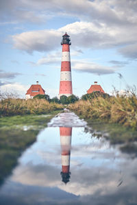 Lighthouse by sea against sky