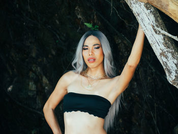 Portrait of young trans woman standing against tree