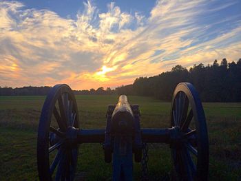 Scenic view of grassy field against sky at sunset