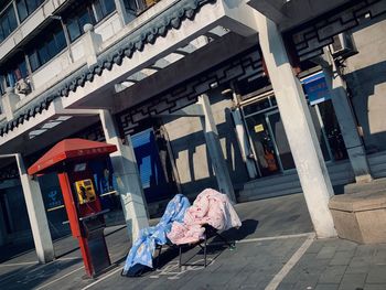 Chairs on footpath by street against buildings in city