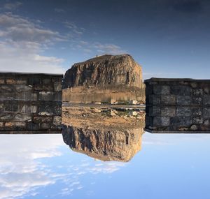 Reflection of rock formations in water against sky