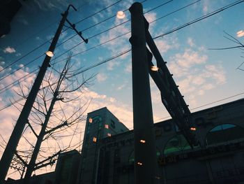 Low angle view of electricity pylon against cloudy sky