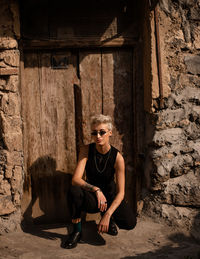 Portrait of young woman sitting near old door 