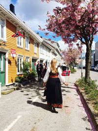 Rear view of woman carrying norwegian flag on footpath