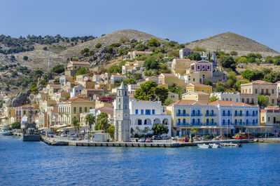 Buildings by sea against clear sky