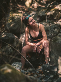 Young woman sitting on rock in forest
