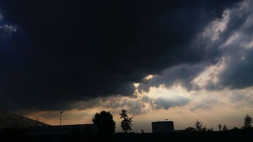 Low angle view of storm clouds over silhouette trees