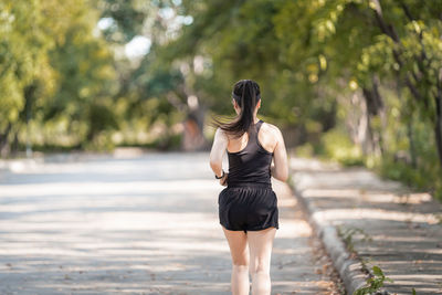 Rear view of woman standing against blurred trees