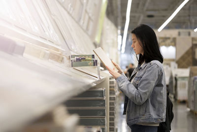 Beautiful young woman chooses flooring in a hardware store to make repairs in the apartment. 