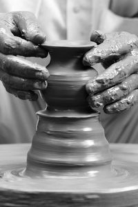 Midsection of man molding a shape on pottery wheel at workshop