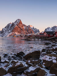 Scenic view of lake by snowcapped mountains against sky during sunset