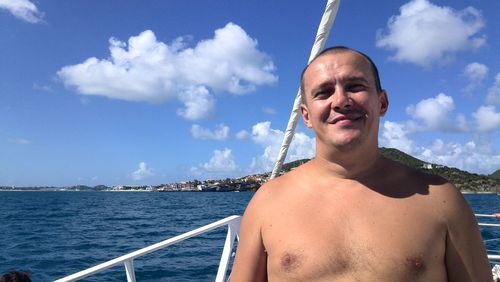 Portrait of shirtless man in sea against sky