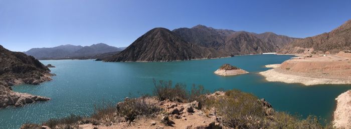 Panoramic view of sea and mountains against clear blue sky