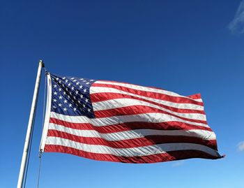 Low angle view of flag against clear blue sky