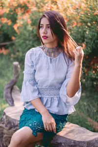 Beautiful young woman sitting against flowering plants