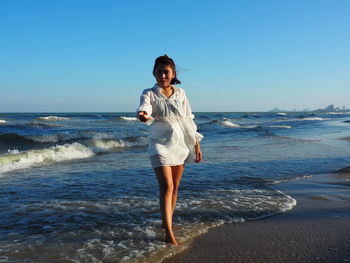 Full length of young woman standing on beach