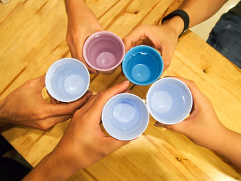 High angle view of people toasting water in glasses over table