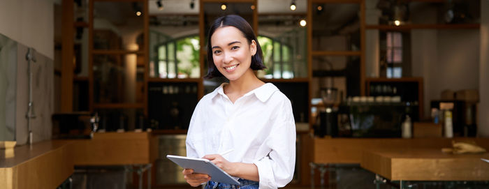 Portrait of young woman standing in library