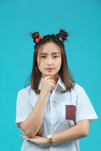 Portrait of young woman standing against blue background