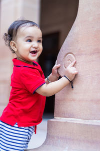 Toddler baby boy cute facial expression standing with wall support in casual appearance at outdoor