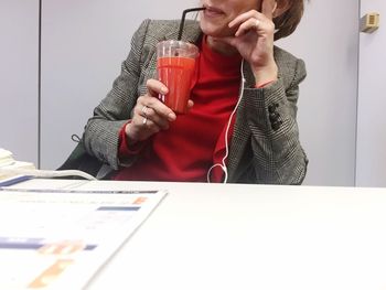 Midsection of man drinking glass on table