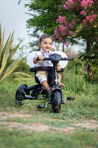 Portrait of boy riding push scooter on field