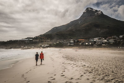 People walking at beach against mountains