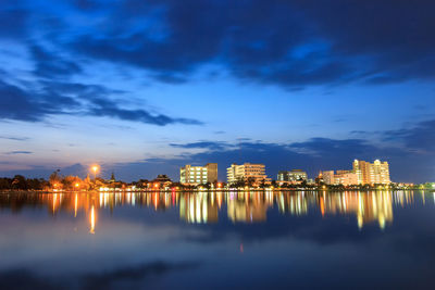 Illuminated city at waterfront during sunset