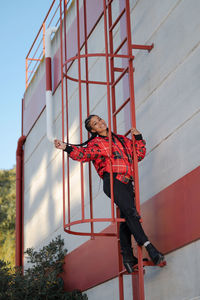 Smiling girl with african braids on a red metal ladder