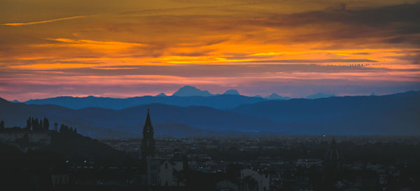 Scenic view of silhouette mountains against romantic sky at sunset