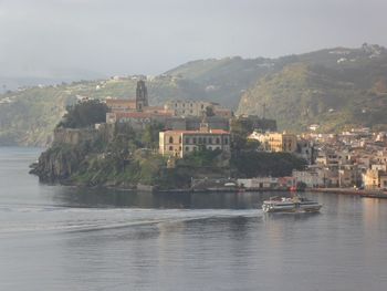 Scenic view of sea by townscape against sky