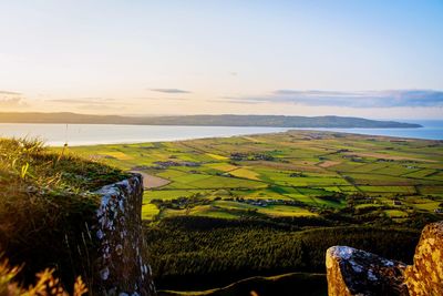 Scenic view of field by sea against sky