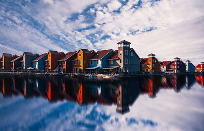 Reflection of buildings in river against sky