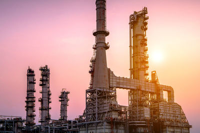 Low angle view of factory against sky during sunset