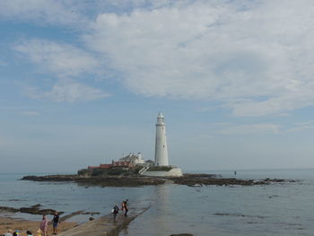 Lighthouse by sea against sky