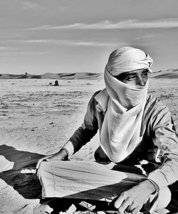 Man wearing headscarf sitting at desert