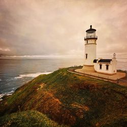 Lighthouse by sea against sky