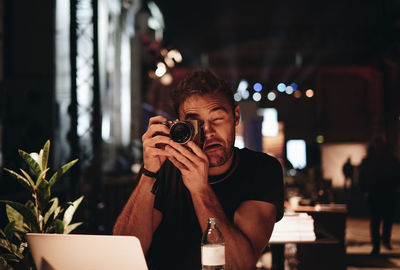 Midsection of man photographing illuminated smart phone