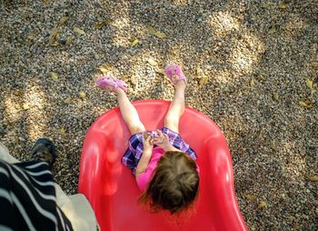 High angle view of girl sitting on red slide at playground