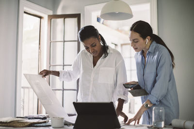 Female designers discussing while working at table in home office