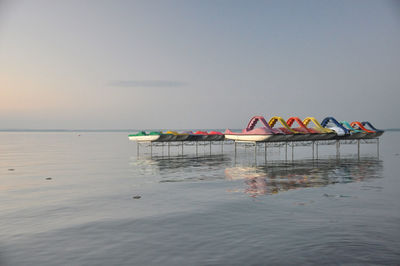 Deck chairs in sea against sky