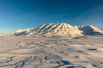 Scenic view of snowcapped mountains against blue sky