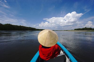 Rear view of person in boat on lake against sky