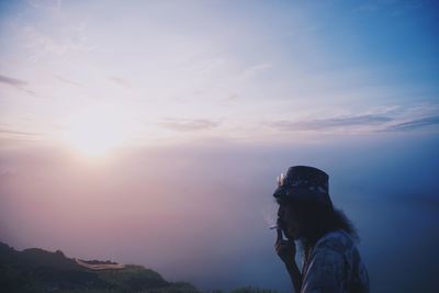 Woman standing on mountain against sky during sunset