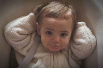 Portrait of cute baby girl in stroller at home