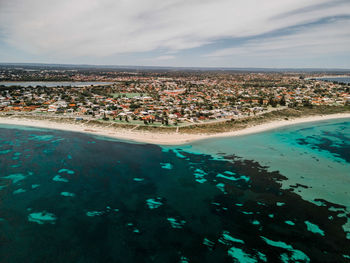 Aerial view of city by sea against sky